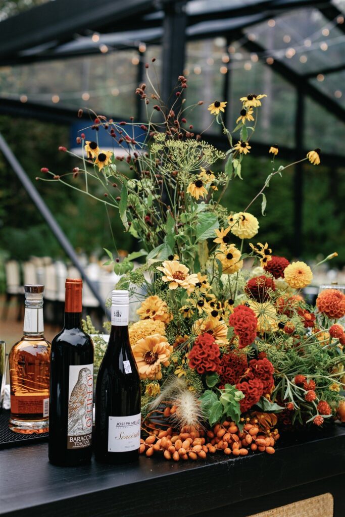 An autumnal bar flower arrangement with brain celosia, dahlias, gerberas, flanked by towering black-eyed Susans, dill, and great bernet.