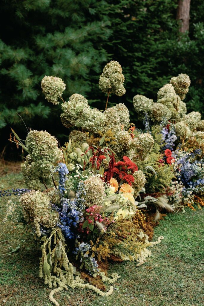 A closeup of Jessica and Rex's overgrown-looking ceremonial floral install—a half circle with hydrangeas, amaranthus, gerberas, delphinium, and more.