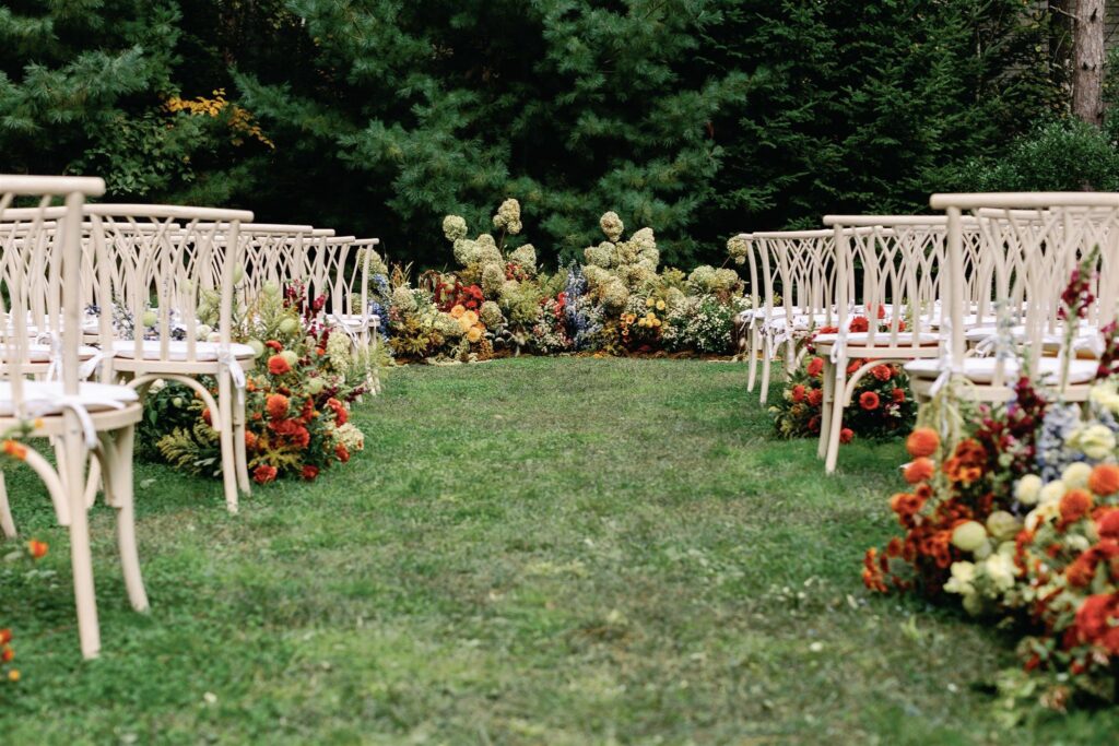 Jessica and Rex's overgrown-looking half circle ceremonial floral install and aisle markers—with hydrangeas, amaranthus, gerberas, delphinium, and more.