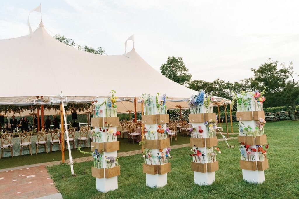 An eclectic, color-blocked escort card wall of bud vase arrangements