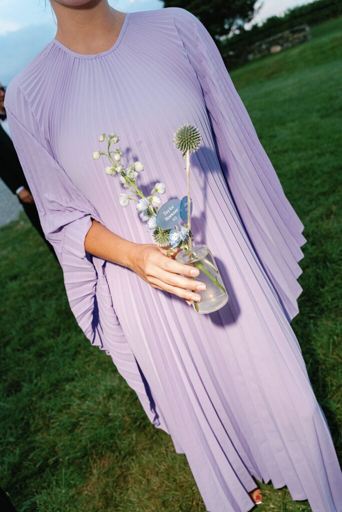 A wedding guest holding her bud vase escort card