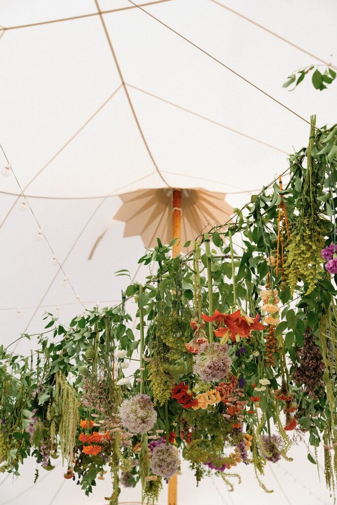 A dense floral overhang above a wedding dance floor and dining area.