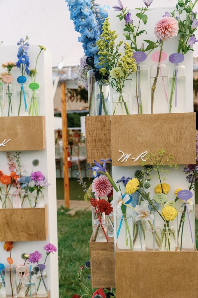 An eclectic, color-blocked escort card wall of bud vase arrangements