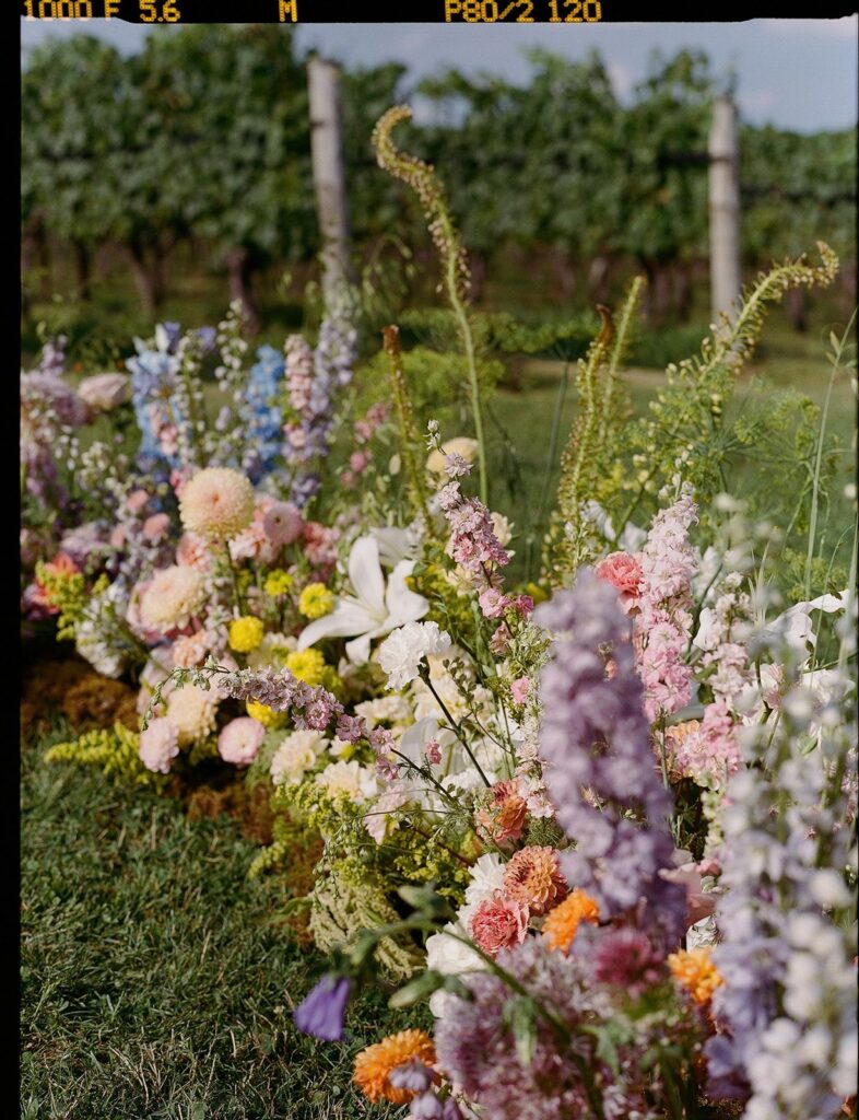 An eclectic, color-blocked rainbow ground arch of flowers