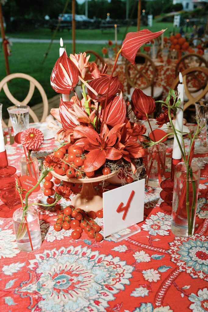 An eclectic, color-blocked tablescape of monochromatic red fruit and flowers