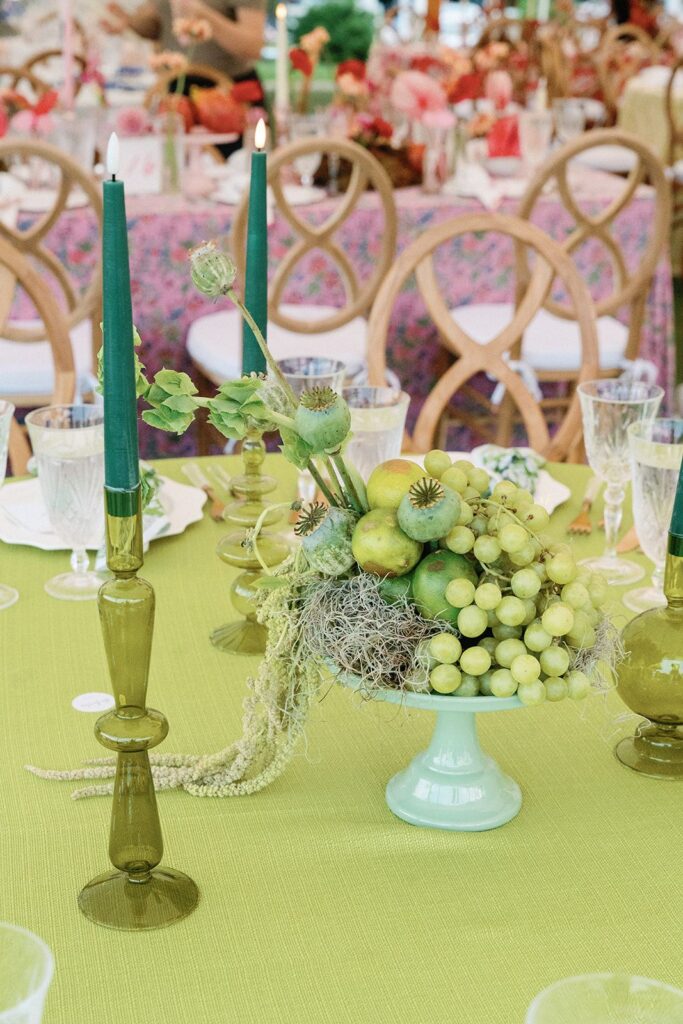 An eclectic, color-blocked tablescape of monochromatic green fruit and flowers