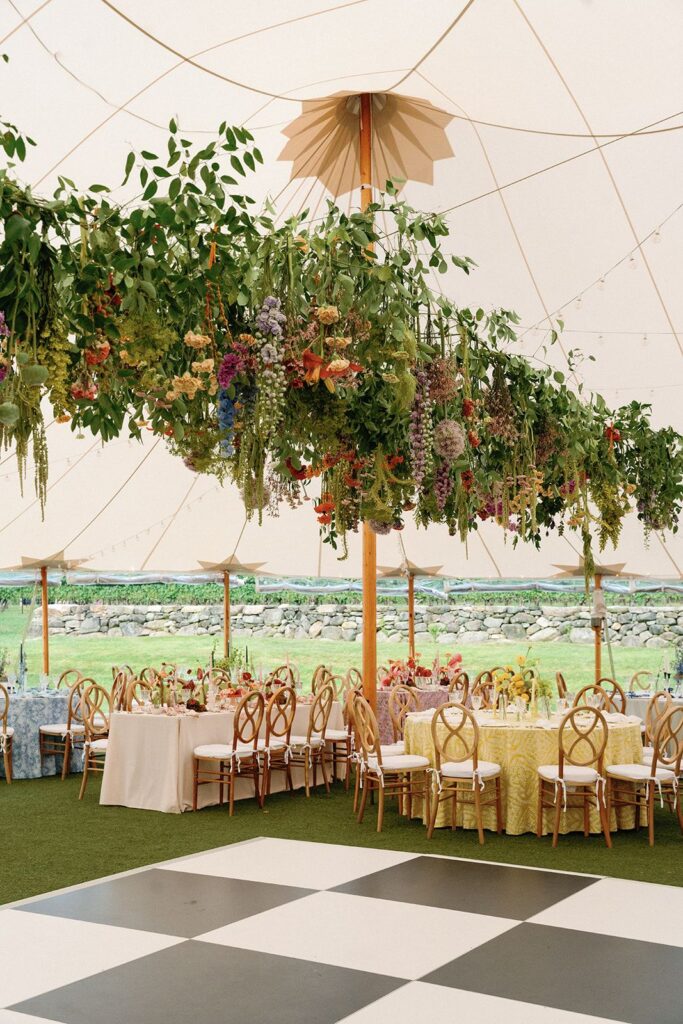 A dense floral overhang above a wedding dance floor and dining area.