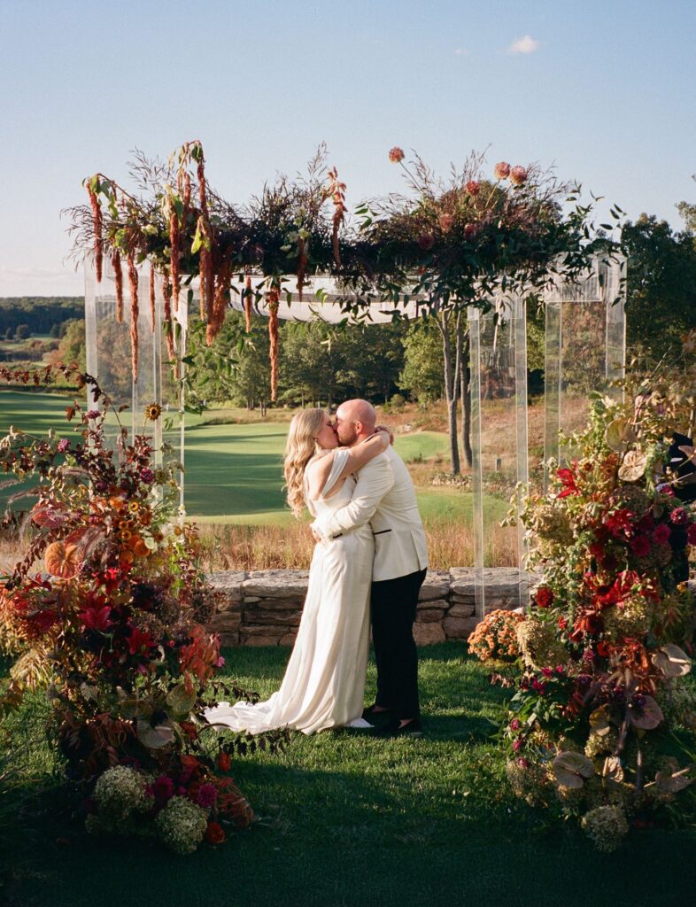 Lacy and Evan embracing after saying  I do beneath a chuppah canopy of hanging mosses and florals.