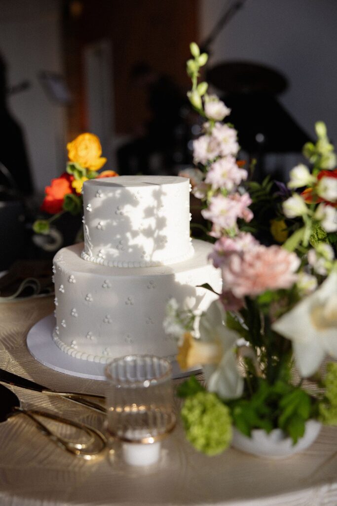 Spring flower ikebana arrangements surrounding a white wedding cake.