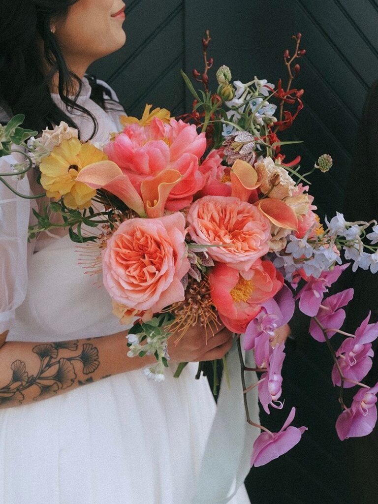 A bridal bouquet featuring orchids, roses, peonies, protea, and more.