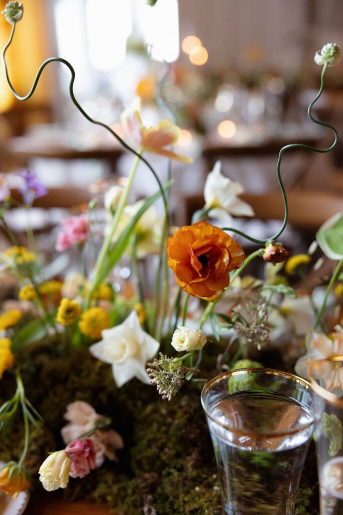 A moss-base centerpiece garland featuring ranunculus, roses, allium, and more.