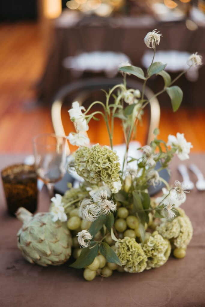 A green floral arrangement of brain celosia, grapes, and artichokes.